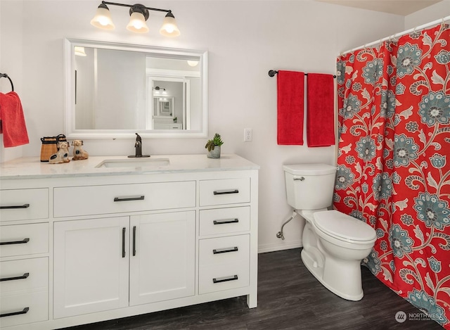 bathroom featuring curtained shower, toilet, wood finished floors, vanity, and baseboards