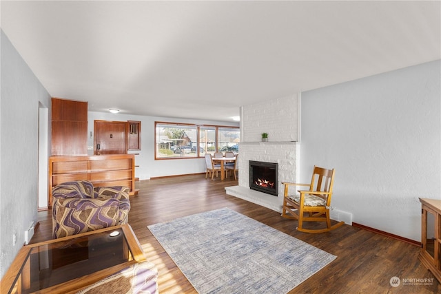 living room with a brick fireplace and dark hardwood / wood-style floors