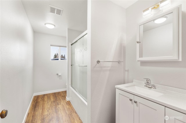 bathroom with enclosed tub / shower combo, vanity, and hardwood / wood-style floors