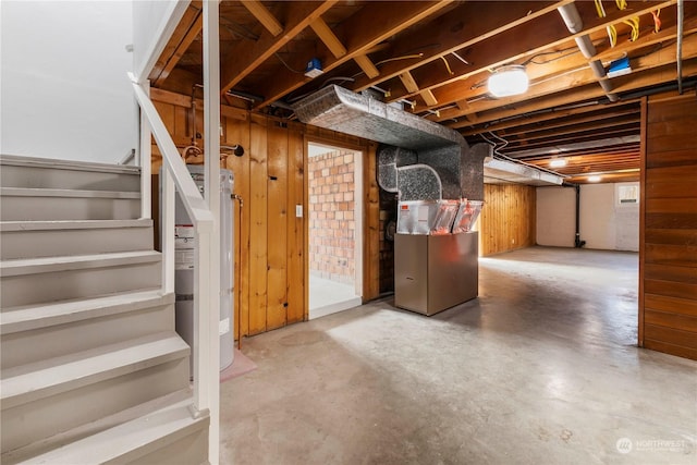 basement featuring heating unit, secured water heater, and wooden walls