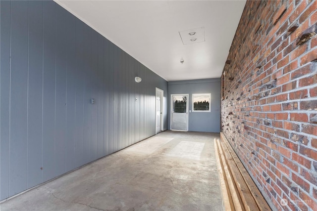 corridor featuring wooden walls and brick wall