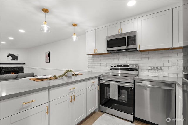 kitchen featuring backsplash, stainless steel appliances, hanging light fixtures, and white cabinets