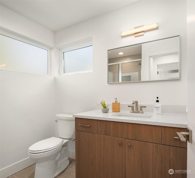 bathroom featuring a shower with door, vanity, and toilet