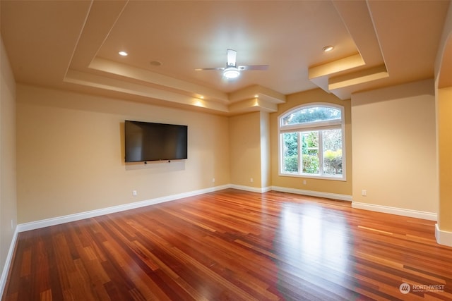 empty room featuring ceiling fan, a raised ceiling, and hardwood / wood-style floors