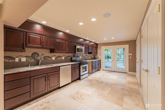 kitchen with sink, appliances with stainless steel finishes, dark brown cabinetry, light stone counters, and french doors