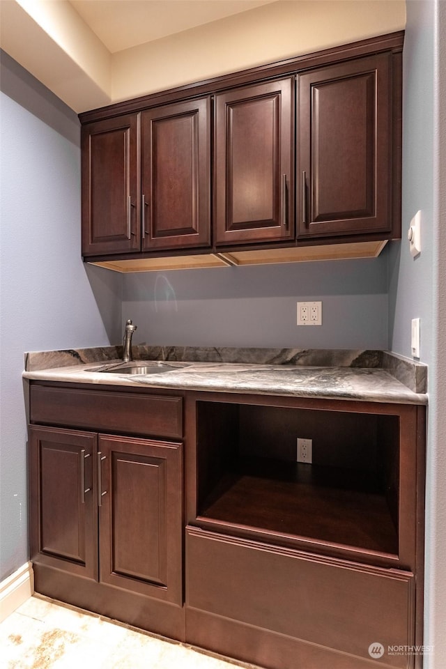 kitchen with dark brown cabinetry, built in desk, and sink