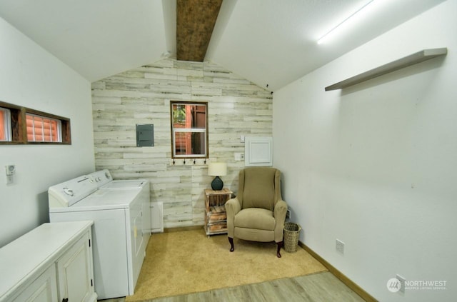 clothes washing area featuring washer and dryer, cabinets, light hardwood / wood-style flooring, and wood walls