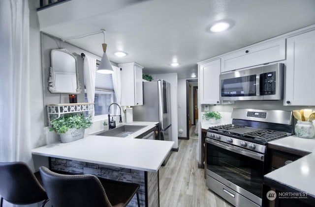 kitchen with white cabinetry, appliances with stainless steel finishes, light hardwood / wood-style flooring, and decorative light fixtures