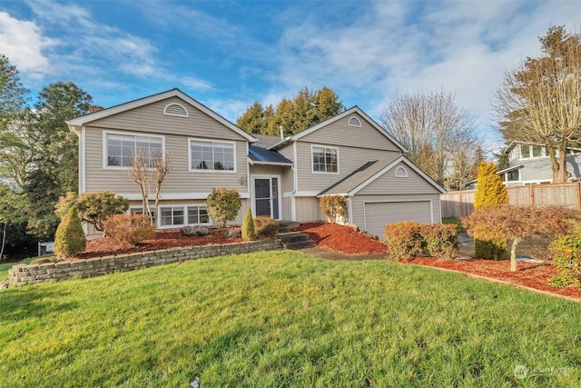 bi-level home featuring a garage and a front lawn