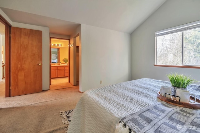 bedroom with light colored carpet, connected bathroom, and vaulted ceiling