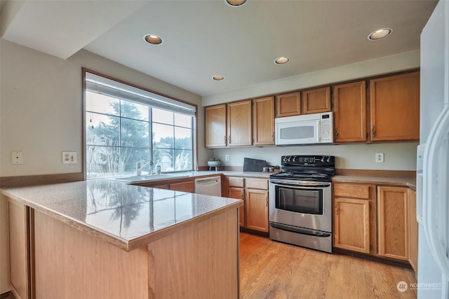 kitchen featuring sink, white appliances, kitchen peninsula, and light wood-type flooring