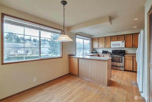 kitchen featuring sink, decorative light fixtures, light wood-type flooring, kitchen peninsula, and white appliances