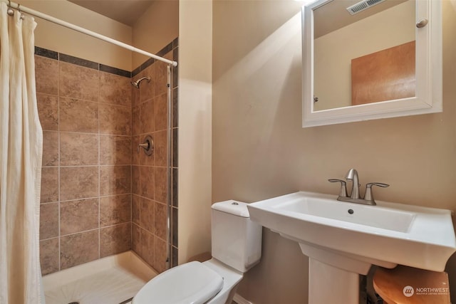 bathroom with sink, curtained shower, and toilet