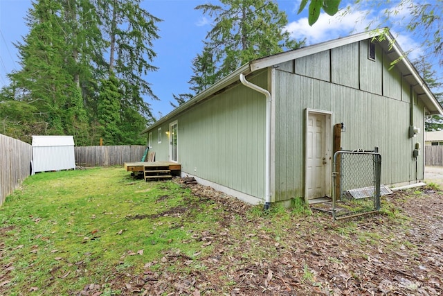 view of side of home featuring an outbuilding, a shed, a lawn, and a fenced backyard