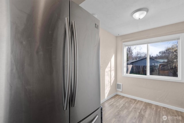 kitchen with light hardwood / wood-style flooring and stainless steel fridge