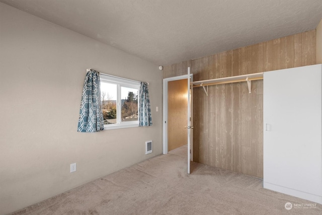 unfurnished bedroom with light colored carpet, a closet, and a textured ceiling