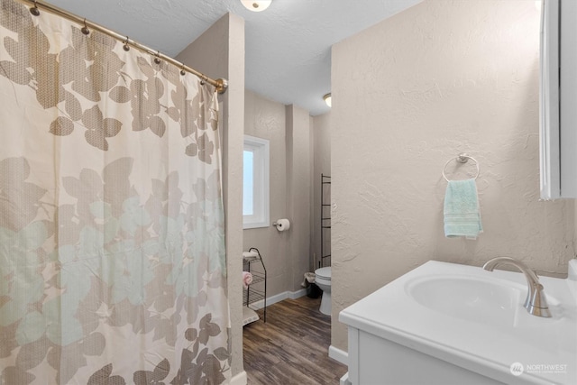 bathroom featuring vanity, hardwood / wood-style flooring, a textured ceiling, and toilet