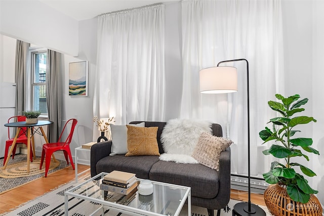 living room with a baseboard heating unit and wood-type flooring