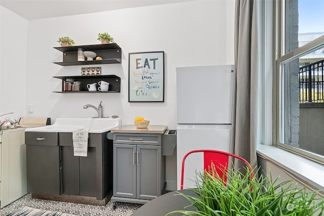 bar featuring washer / dryer, white fridge, sink, and gray cabinetry