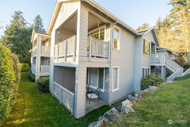 back of house with a balcony and a yard