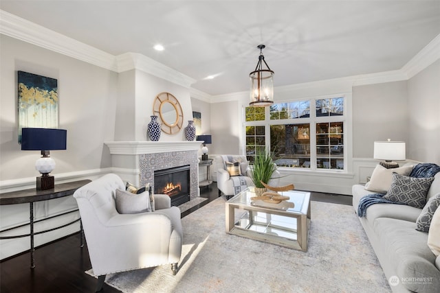 living room with crown molding, wood-type flooring, and a tiled fireplace