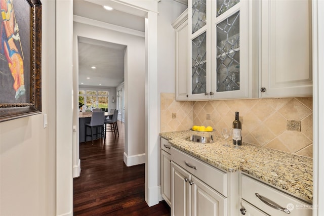 bar featuring white cabinetry, backsplash, dark wood-type flooring, and light stone countertops