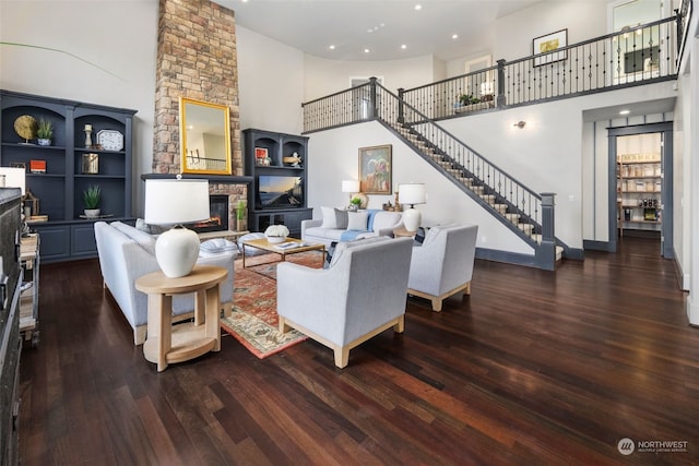 living room with a towering ceiling, a fireplace, and dark hardwood / wood-style floors