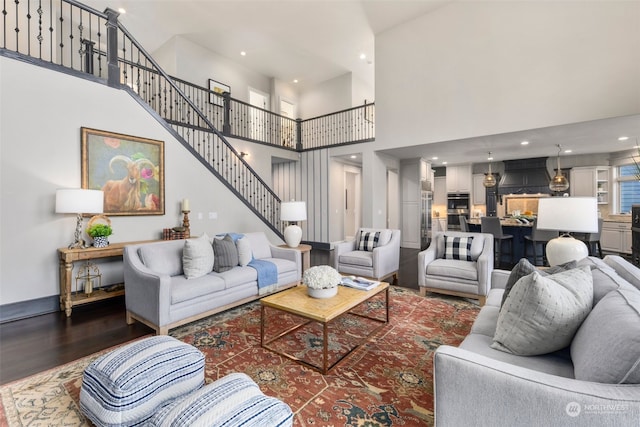 living room featuring a towering ceiling and dark wood-type flooring