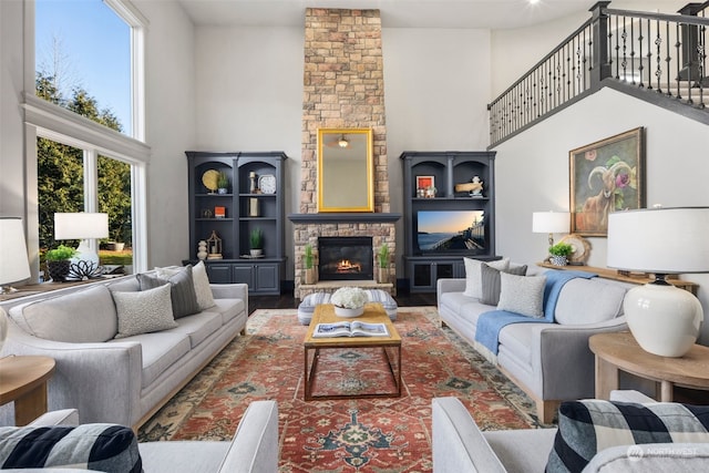 living room featuring wood-type flooring, a towering ceiling, and a fireplace