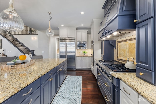 kitchen featuring white cabinetry, blue cabinets, built in appliances, and decorative light fixtures