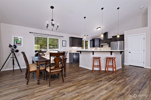 dining room with dark hardwood / wood-style flooring, a notable chandelier, and lofted ceiling