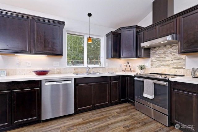 kitchen featuring sink, dark wood-type flooring, hanging light fixtures, stainless steel appliances, and dark brown cabinetry