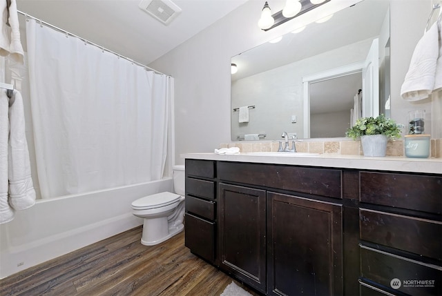 full bathroom featuring hardwood / wood-style flooring, vanity, shower / bath combo with shower curtain, and toilet