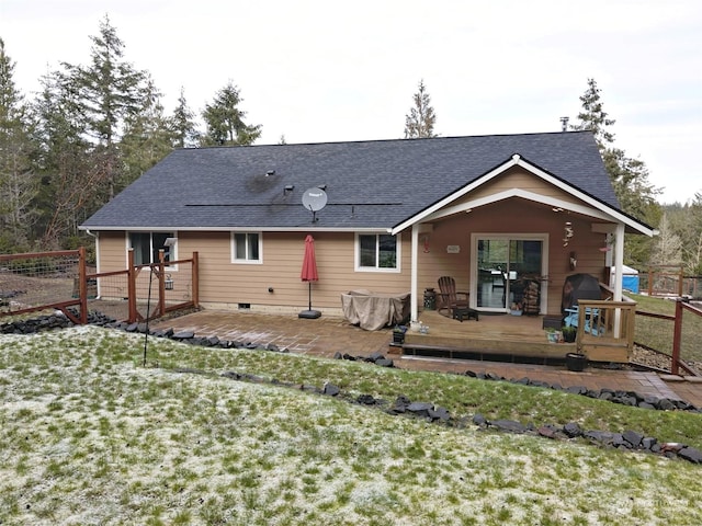 back of property with a wooden deck and a lawn