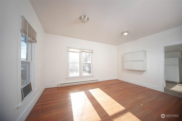 unfurnished room with baseboard heating, a healthy amount of sunlight, and hardwood / wood-style flooring