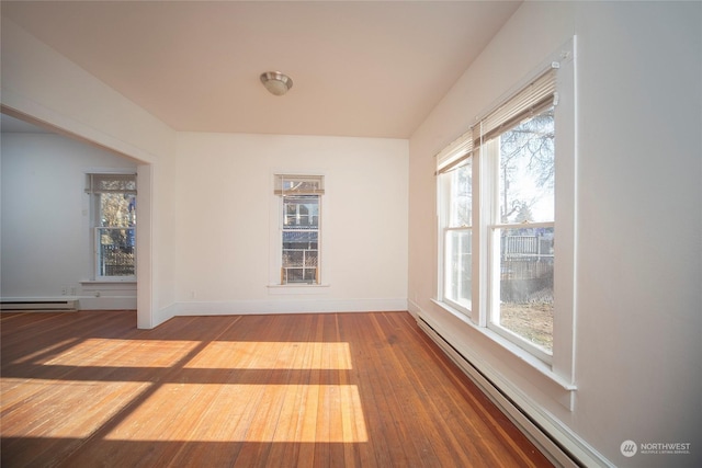 unfurnished room with a baseboard radiator, wood-type flooring, and baseboards