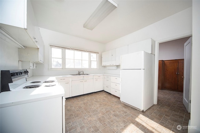 kitchen with white appliances, a sink, light countertops, stone finish floor, and white cabinetry