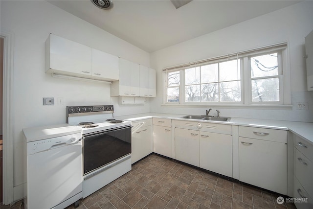 kitchen featuring white appliances, white cabinets, light countertops, and a sink