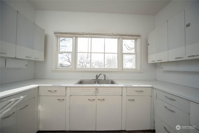 kitchen with white cabinets, light countertops, and a sink