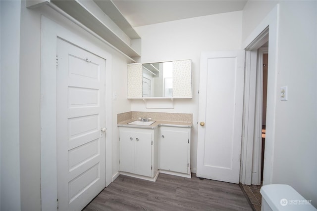 kitchen featuring a sink, dark wood-type flooring, white cabinets, and light countertops