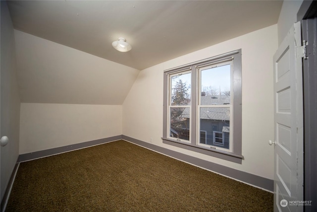 bonus room featuring dark carpet, baseboards, and vaulted ceiling