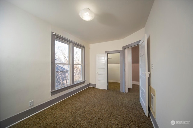 unfurnished bedroom with baseboards and dark colored carpet