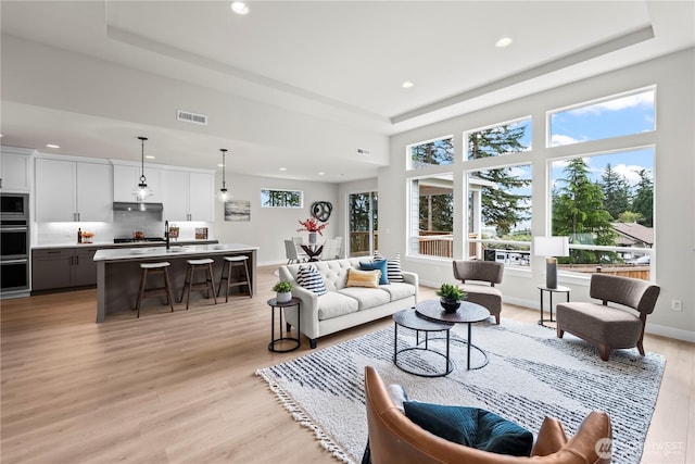 6612 6th St E, Tacoma, WA 98424 - living room with a tray ceiling, recessed lighting, light wood-type flooring, and baseboards