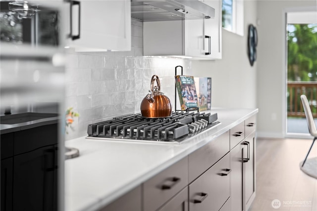 6612 6th St E, Tacoma, WA 98424 - kitchen featuring range hood, stainless steel gas stovetop, light countertops, decorative backsplash, and white cabinetry