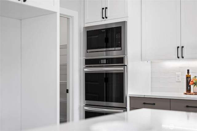 6612 6th St E, Tacoma, WA 98424 - kitchen with built in microwave, light countertops, backsplash, white cabinets, and fridge