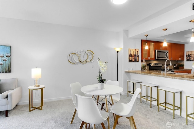 dining space featuring baseboards and light colored carpet