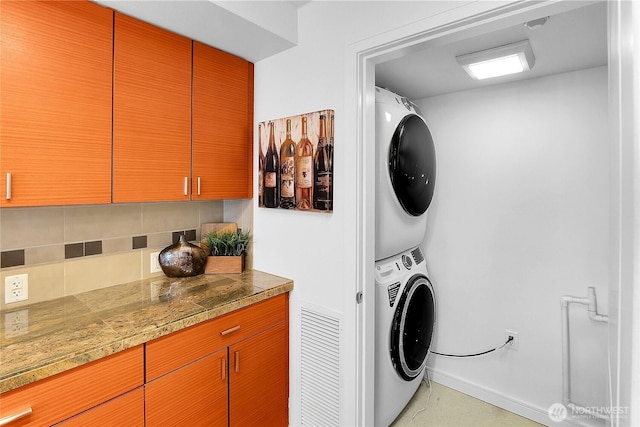 washroom with baseboards and stacked washer / drying machine