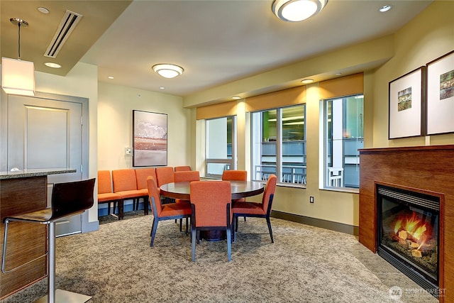 dining space featuring baseboards, visible vents, carpet flooring, and a glass covered fireplace