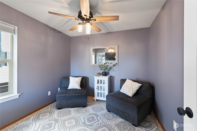 living area with baseboards, a ceiling fan, and carpet flooring