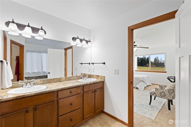 ensuite bathroom with double vanity, connected bathroom, baseboards, and a sink